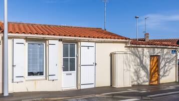 A building with a tiled roof, two white doors, a small window, and a utility box.