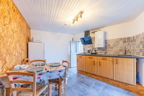 Cocina compacta con armarios de madera, salpicadero de azulejos y comedor con una mesa preparada para cuatro.