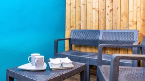 Un espace détente avec deux chaises et une table, un mur bleu et un fond en panneaux de bois.