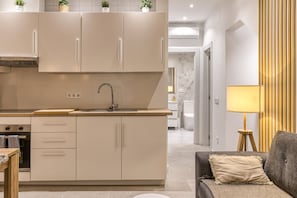 Eine moderne Küche mit einer zentralen Kochinsel, integrierten Geräten und einem Essbereich mit einer Couch und einer Lampe.