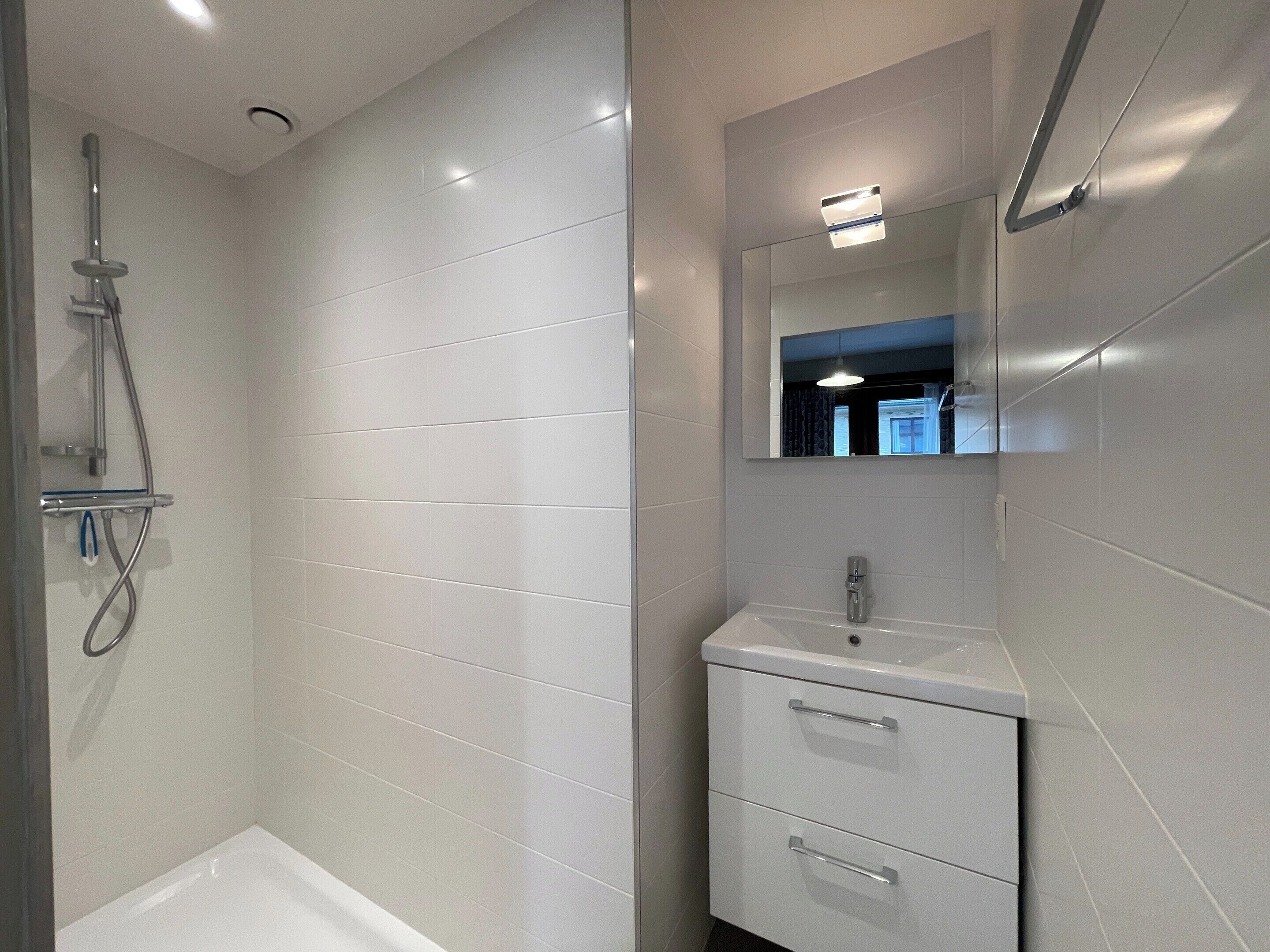 Un bagno moderno con doccia, lavandino e specchio.