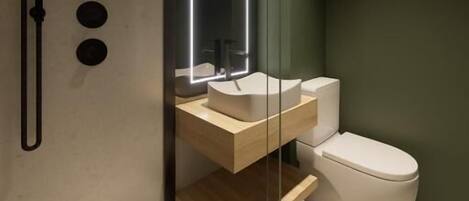 Un baño moderno con cabina de ducha de vidrio, tocador de madera y un inodoro blanco.
