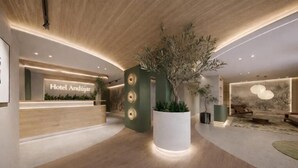 A modern hotel lobby with a reception desk, a large potted plant, and a seating area with a view of the outdoors. - Hospedium GL Hotel Andújar (Andújar)