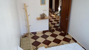 A room with a checkered floor, a wooden coat rack, a small ship model, and a mirror on the wall. - titryte (Aourir)