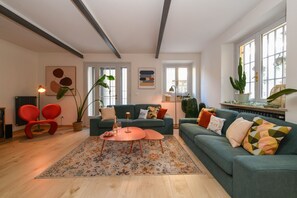 A spacious living room with a sofa, armchairs, and a coffee table. There are large windows, a radiator, and a potted plant. - MGH Luxury - Sunset Lakeview House Desenzano (Desenzano del Garda)