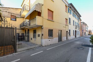 A street view of a building with a balcony, a gated entrance, and a clear road. - MGH Luxury - Sunset Lakeview House Desenzano (Desenzano del Garda)