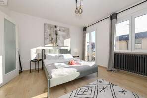 A modern bedroom with a bed, bedside tables, a radiator, and a large window. - MGH Luxury - Sunset Lakeview House Desenzano (Desenzano del Garda)