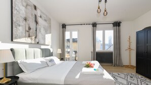 A modern hotel room with a large bed, a view of the city, and a black wardrobe. - MGH Luxury - Sunset Lakeview House Desenzano (Desenzano del Garda)