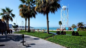A coastal promenade with palm trees, a Ferris wheel, and a modern tower structure. - Serene 1-bedroom apartment in Dubai perfect for your getaway (Dubai)