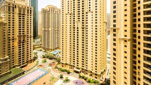 A high-rise residential building with multiple floors, a central courtyard with a basketball court, and surrounding greenery. - Serene 1-bedroom apartment in Dubai perfect for your getaway (Dubai)