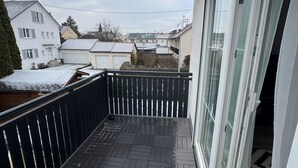 Ein Balkon mit Blick auf benachbarte Häuser und einen bewölkten Himmel.