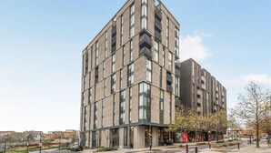 Un edificio moderno a più piani con un design d'angolo ben evidente, ampie finestre e balconi.