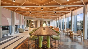 Un'ampia sala conferenze con un lungo tavolo, sedie verdi e soffitto in legno.