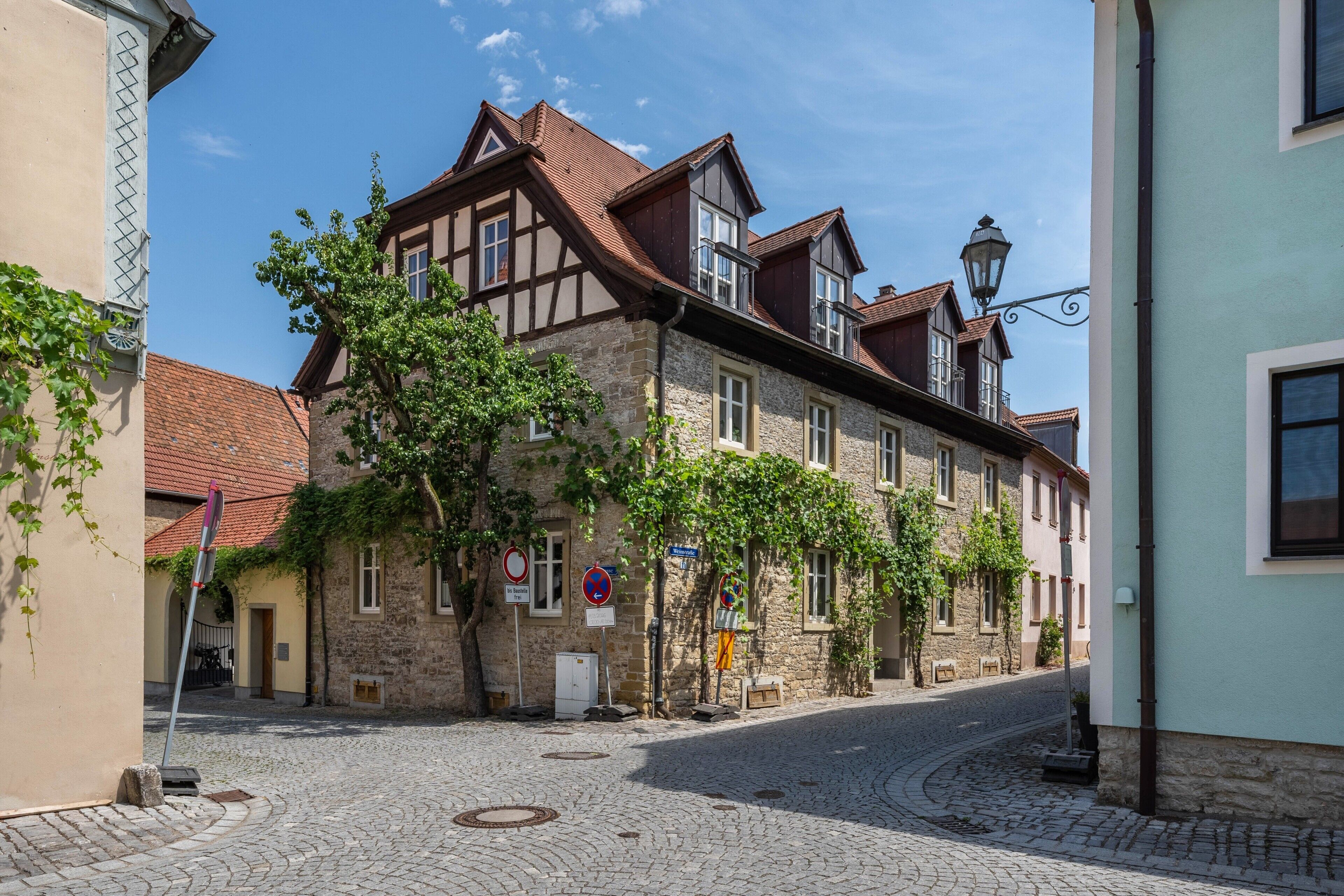 Een straat met kinderkopjes, historische gebouwen, een lantaarnpaal en straatnaambordjes.