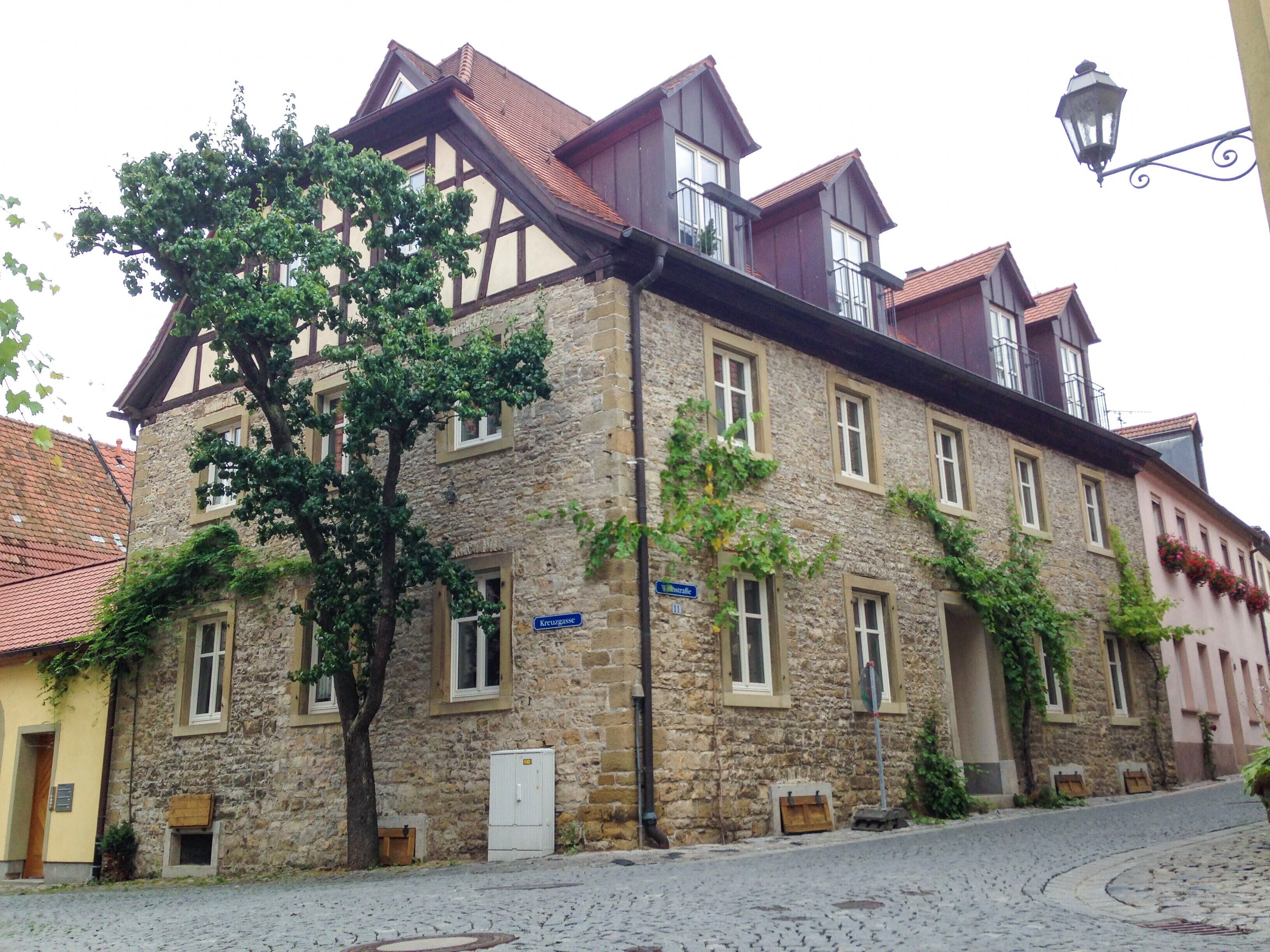 Un edificio histórico de piedra con un estilo arquitectónico europeo tradicional, que destaca por su pronunciado tejado a dos aguas y numerosas ventanas.