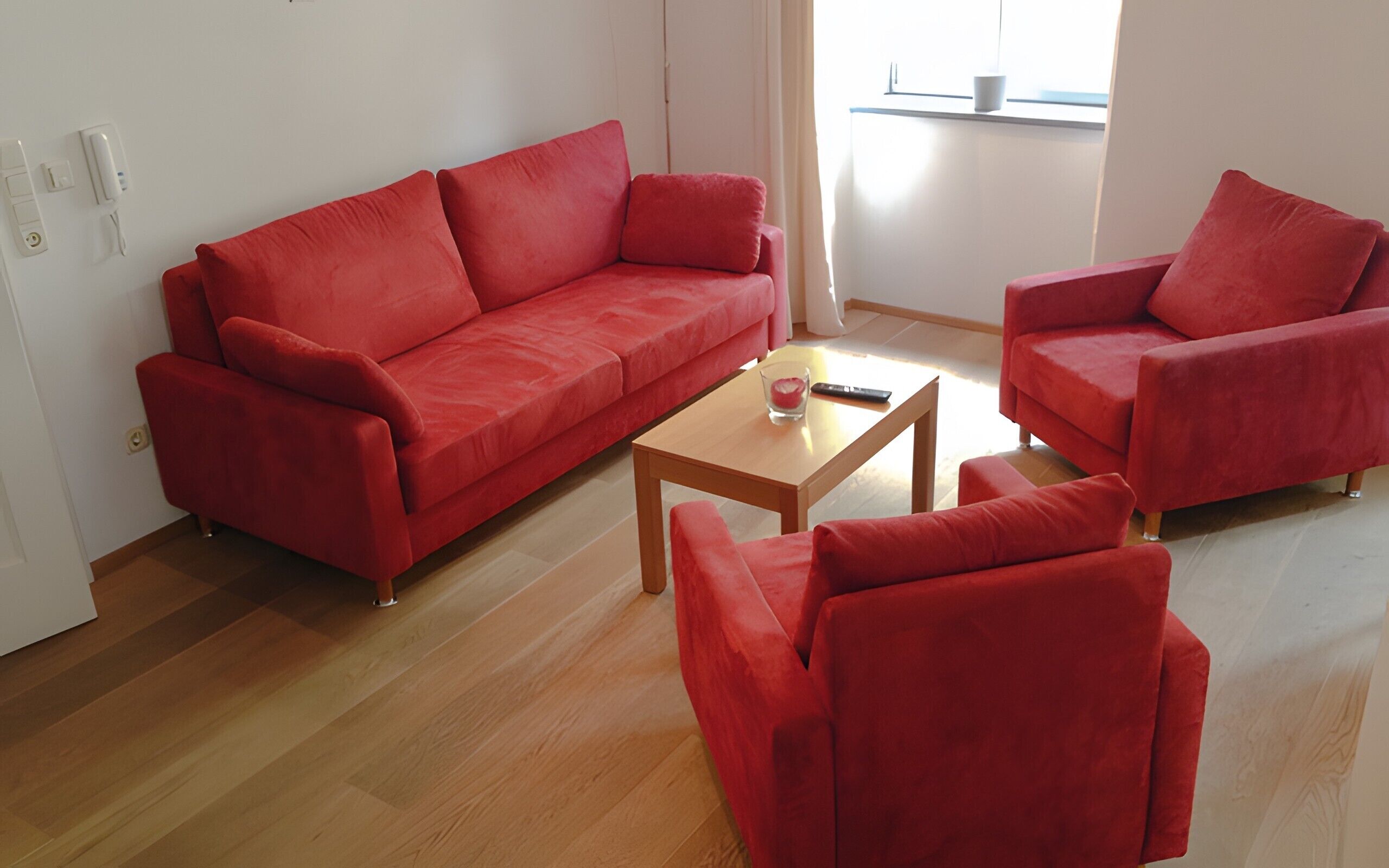 Una sala de estar con un sofá rojo, un sillón a juego y una mesa de centro de madera.