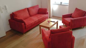 Una sala de estar con un sofá rojo, un sillón a juego y una mesa de centro de madera.
