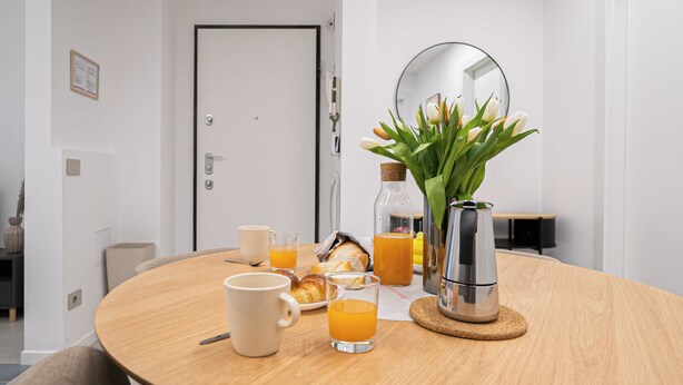 A breakfast setup with a coffee maker, croissants, and orange juice on a wooden table. - Italianway Comfort - Certosa 19 (Milan)