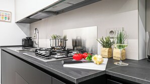A modern kitchen with a gas stove, a coffee machine, and fresh produce on the counter. - Italianway Comfort - Certosa 19 (Milan)