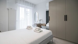 A modern hotel room with a large bed, a desk, a mirror, and a wardrobe. - Italianway Comfort - Certosa 19 (Milan)