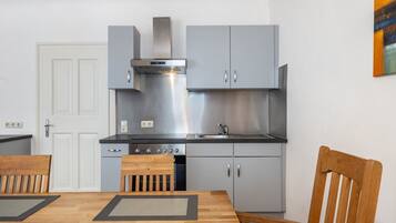 Una cocina moderna con gabinetes grises, electrodomésticos de acero inoxidable y una mesa de comedor de madera con sillas.