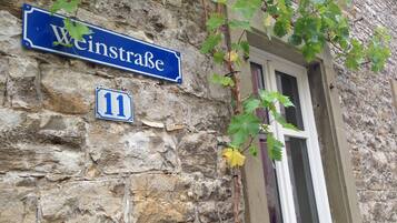 Un bâtiment en pierre, avec une plaque de rue bleue indiquant « Weinstrasse » et une plus petite plaque portant le numéro « 11 ».