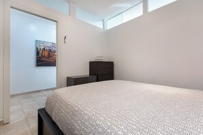 Ein modernes Schlafzimmer mit einem großen Bett, einem Nachttisch, einer Kommode und einem Stadtbild an der Wand.