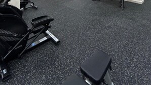 Ein Fitnessstudio mit Laufbändern, einer Bank und Kraftgeräten.