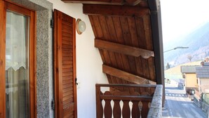 A wooden balcony with a view of a mountain and a street. - Apartment 'The Wild Deer Retreat' with Mountain View and Balcony (Schilpario)