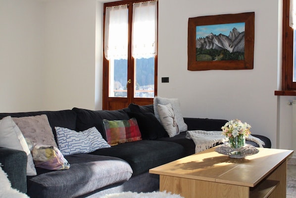 A living room with a sofa, a coffee table, and a painting on the wall.