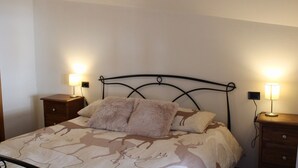 A bed with a metal headboard, two bedside tables with lamps, a wooden dresser, and a patterned bedspread. - Apartment 'The Wild Deer Retreat' with Mountain View and Balcony (Schilpario)