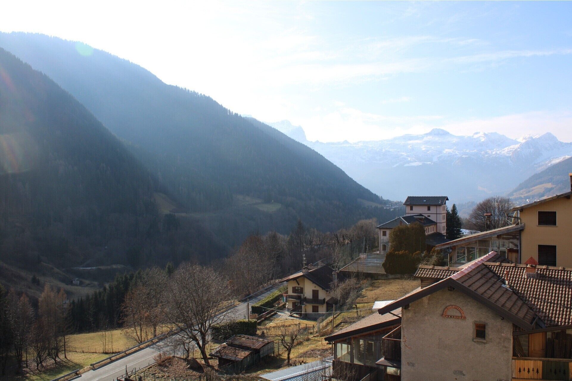 A mountainous landscape with residential buildings, including a house with a balcony and a building with a tiled roof.