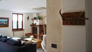 A living room with a fireplace, a sofa, a coffee table, and a wall-mounted shelf. - Apartment 'The Wild Deer Retreat' with Mountain View and Balcony (Schilpario)