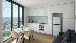 Eine moderne Küche mit weißen Schränken, einem Esstisch mit Stühlen, einer Couch und Blick auf die Stadt.