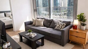 Ein modernes Wohnzimmer mit einem grauen Sofa, einem schwarzen Couchtisch und einem hölzernen Nachttisch.