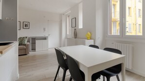 En modern lägenhet med matplats, pentry och utsikt över en gul byggnad.