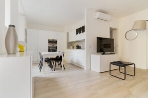 A modern kitchen with white cabinetry, a dining area with a table and chairs, and a small black table. - GuestHost - A bright 50 square meters apartment, perfect for four people, located on the first floor of a building with an elevator (NOT accessible to disabled guests).The property is located near the Central Station, one of the main hubs for getting aro (Milan)
