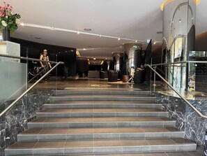 Una hall d'albergo con scalinate in marmo, una reception e un design d'interni moderno.