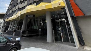 A modern building with a prominent entrance, large pillars, and a distinctive yellow awning. - Skyline Stays | L22 1BR Free Parking near Crwon (Southbank)