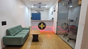 Ein Empfangsbereich mit einem grünen Sofa, einem Holztisch und einer Rezeption mit einem Schild.