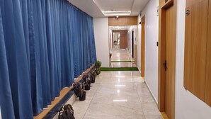 Ein Hotelgang mit blauen Vorhängen, Holztüren und einem gefliesten Boden.