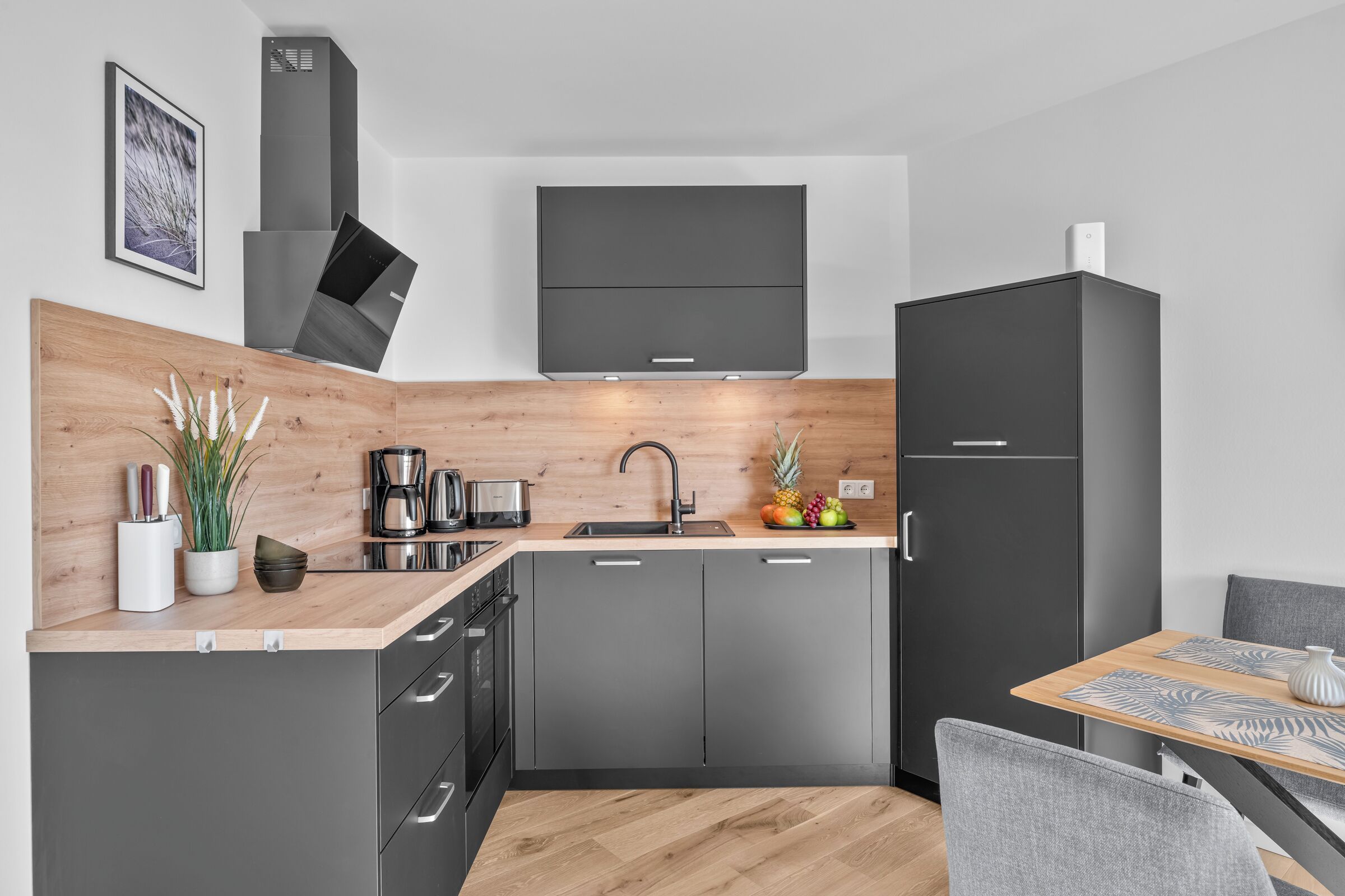 Une cuisine moderne avec un plan de travail en bois, des appareils en acier inoxydable et des meubles gris.