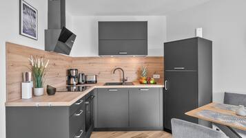 Une cuisine moderne avec un plan de travail en bois, des appareils en acier inoxydable et des meubles gris.