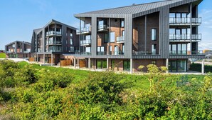 A modern multi-story residential building with balconies and large windows. - The View C05 Sonnengruß - Balcony, garden furniture, shared. Sauna, car park (Dagebüll)