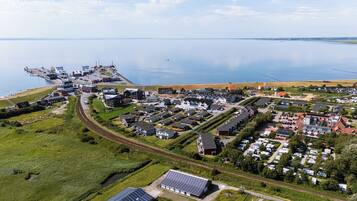 An aerial view of a coastal town with residential buildings, a marina, and a railway line.