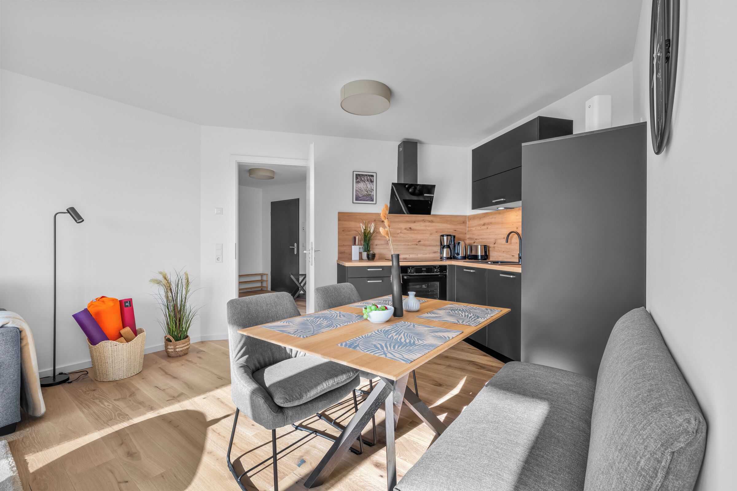 A modern kitchen with a built-in stove, a dining area with a table and chairs, and a living area with a sofa.