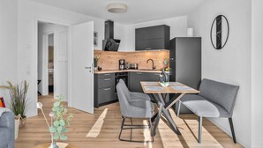 A modern kitchen with dark cabinets, a wooden countertop, and a built-in oven. - The View C05 Sonnengruß - Balcony, garden furniture, shared. Sauna, car park (Dagebüll)