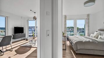 Une chambre moderne avec un grand lit, une télévision et une vue sur la ville.