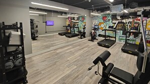 Une salle de sport équipée de tapis de course, de poids et d’un miroir.