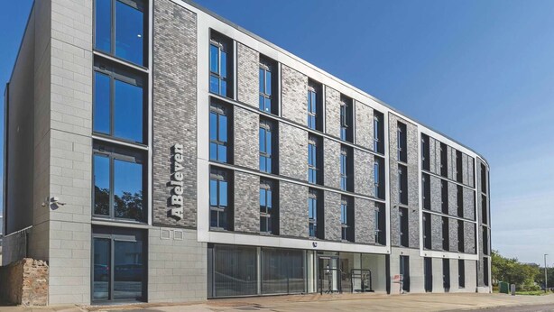 Un bâtiment moderne doté d’un toit plat, de grandes fenêtres et d’une façade en briques.